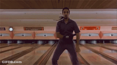 A Man Is Standing On A Bowling Alley Holding A Bowling Ball In His Hand GIF