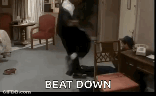 A Man Is Standing On A Chair In A Living Room With The Words `` Beat Down '' Written On The Screen . GIF