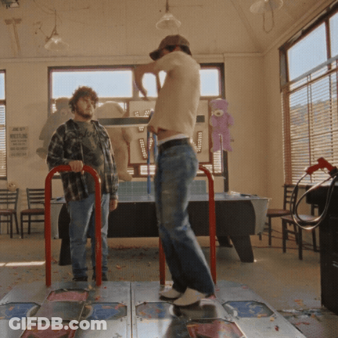 A Man Is Standing On A Dance Floor In Front Of A Sign That Says No Smoking GIF