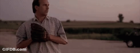 A Man Is Standing On A Dirt Road Holding A Baseball Mitt . GIF