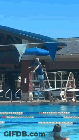 A Man Is Standing On A Diving Board In A Swimming Pool GIF