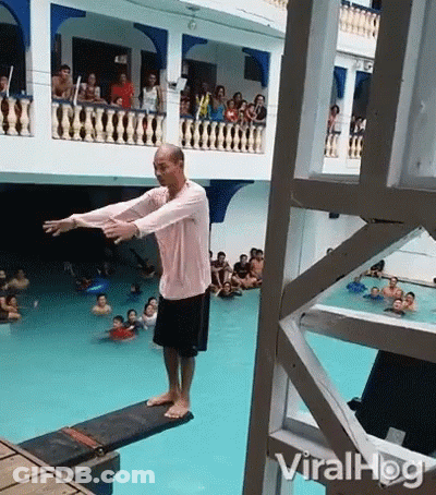 A Man Is Standing On A Diving Board In Front Of A Crowd Of People . GIF