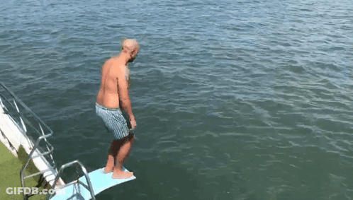 A Man Is Standing On A Diving Board Into The Water GIF
