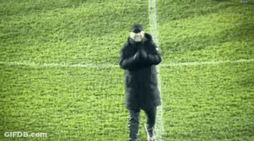 A Man Is Standing On A Soccer Field With His Hands Folded In Front Of Him . GIF