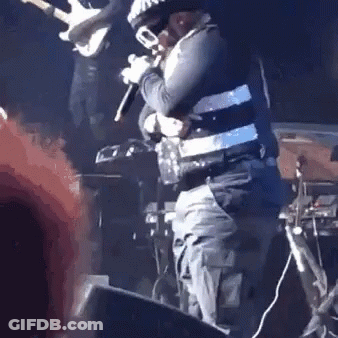 A Man Is Standing On A Stage Holding A Microphone And A Trumpet . GIF