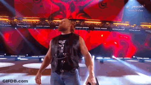 A Man Is Standing On A Stage Holding A Microphone . GIF
