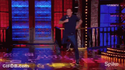 A Man Is Standing On A Stage Holding A Microphone While Dancing . GIF