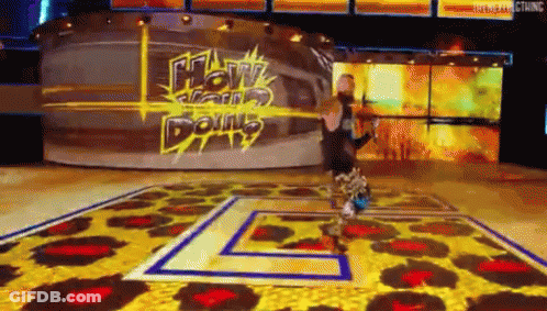 A Man Is Standing On A Stage In Front Of A Sign That Says ' How Can I Do N't ' . GIF