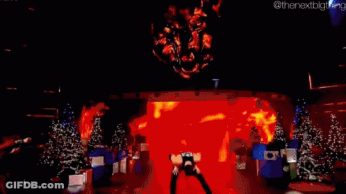 A Man Is Standing On A Stage In Front Of Christmas Trees . GIF
