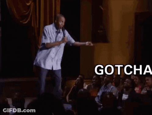 A Man Is Standing On A Stage With A Microphone In Front Of A Crowd Of People And Says Gotcha Bitch . GIF