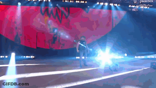 A Man Is Standing On A Stage With A Peacock Logo In The Background GIF