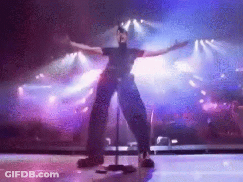 A Man Is Standing On A Stage With His Arms Outstretched . GIF