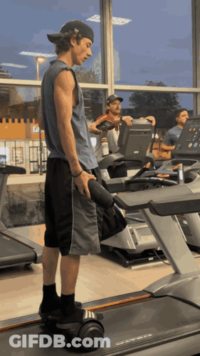 A Man Is Standing On A Treadmill Holding A Dumbbell In A Gym GIF