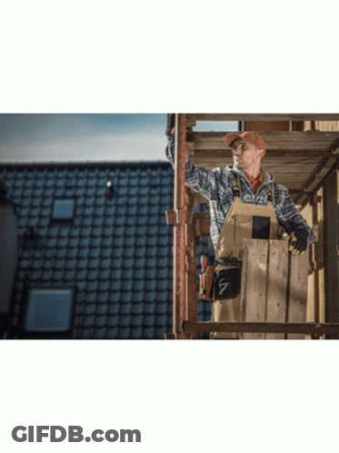 A Man Is Standing On A Wooden Scaffolding Looking Up At The Sky GIF
