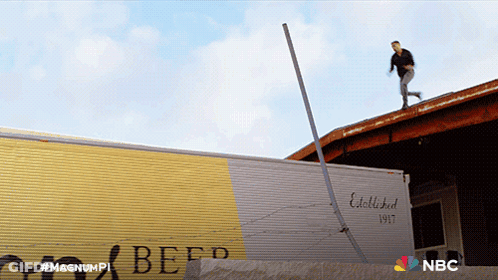 A Man Is Standing On The Roof Of A Building Next To A Beef Truck GIF