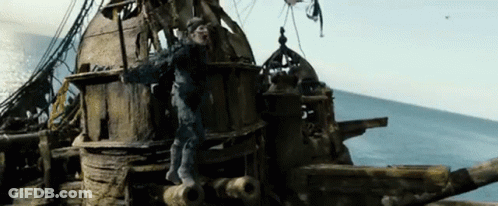 A Man Is Standing On The Side Of A Wooden Ship In The Ocean . GIF