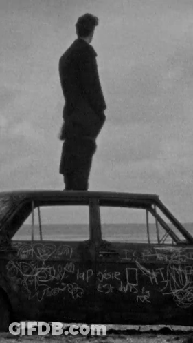 A Man Is Standing On Top Of A Car With Graffiti On It GIF