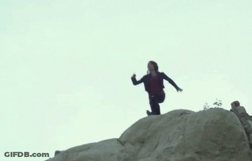 A Man Is Standing On Top Of A Large Rock . GIF