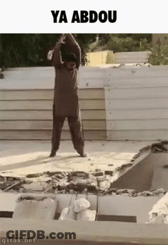 A Man Is Standing On Top Of A Pile Of Concrete With The Words Ya Abdou Written Above Him . GIF