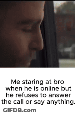 A Man Is Staring Out Of A Window While Talking On A Phone . GIF