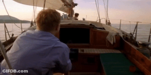 A Man Is Steering A Boat In The Ocean GIF