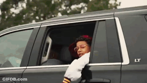 A Man Is Sticking His Head Out Of The Window Of A Car . GIF
