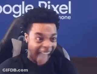 A Man Is Sticking His Tongue Out While Sitting In Front Of A Computer Screen . GIF