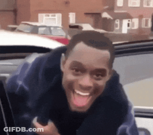 A Man Is Sticking His Tongue Out While Sitting In The Back Seat Of A Car . GIF
