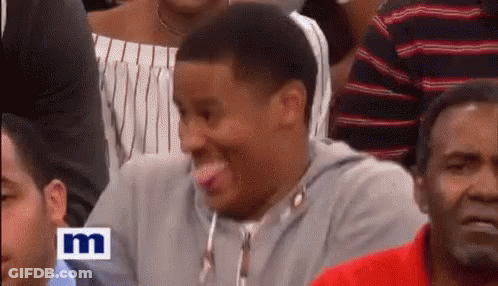 A Man Is Sticking Out His Tongue While Sitting In A Crowd . GIF