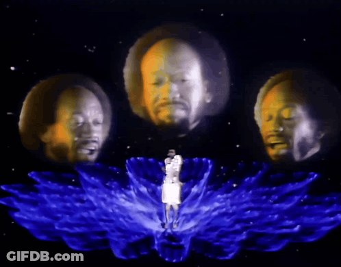 A Man Is Surrounded By Three Heads That Are Projected On To Him GIF