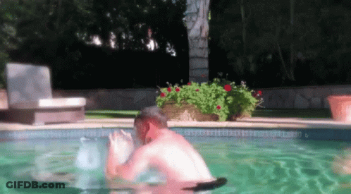 A Man Is Swimming In A Swimming Pool With A Chair In The Background . GIF