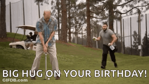A Man Is Swinging A Golf Club On A Golf Course While Another Man Holds A Golf Bag . GIF