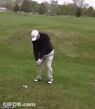 A Man Is Swinging A Golf Club On A Golf Course While Dancing . GIF