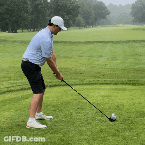 A Man Is Swinging A Golf Club On A Green GIF