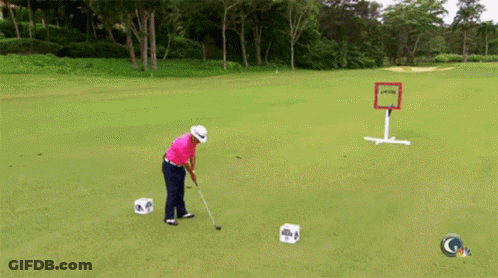 A Man Is Swinging A Golf Club On A Green With A Sign In The Background That Says Gtv GIF