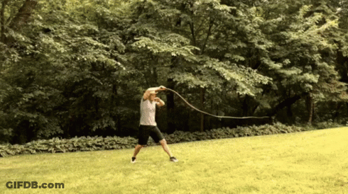 A Man Is Swinging A Rope In A Park GIF