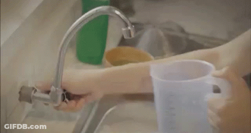 A Man Is Taking A Bath In A Bathtub And Holding A Bucket Of Water . GIF