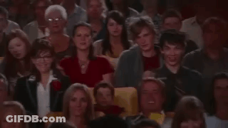 A Man Is Taking A Picture Of A Crowd Of People In A Theatre . GIF