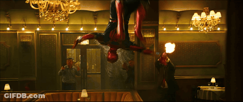 A Man Is Taking A Picture Of A Man In A Spiderman Costume In A Restaurant GIF