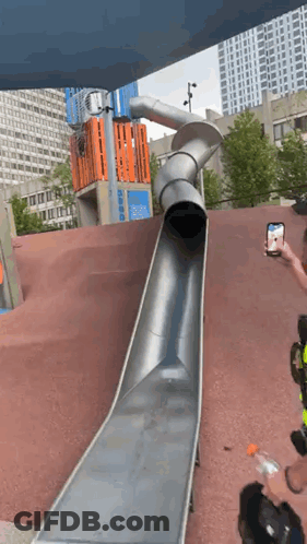 A Man Is Taking A Picture Of A Slide At A Playground GIF