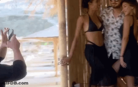 A Man Is Taking A Picture Of A Woman In A Bikini With The Hashtag #Lohan Beach Club GIF