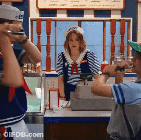 A Man Is Taking A Picture Of A Woman In A Sailor Costume At An Ice Cream Parlor . GIF