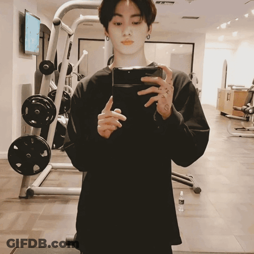 A Man Is Taking A Picture Of Himself In A Gym With His Phone GIF