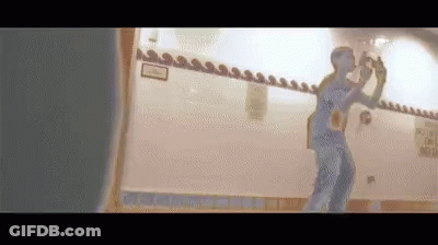 A Man Is Taking A Picture Of Himself In A Mirror . GIF