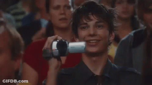 A Man Is Taking A Picture Of Himself With A Camera In A Crowd . GIF