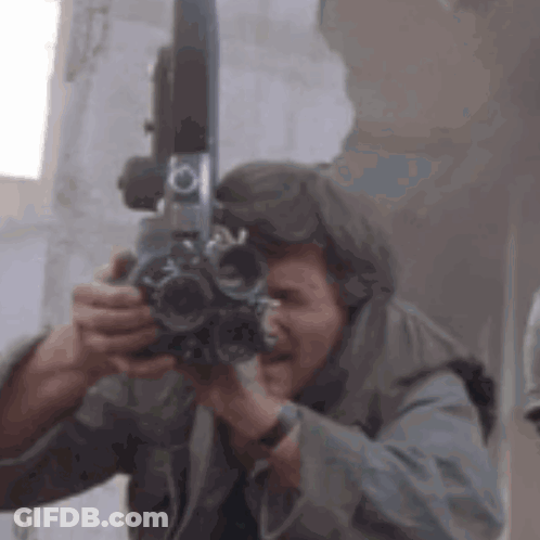 A Man Is Taking A Picture With A Camera In His Hands . GIF