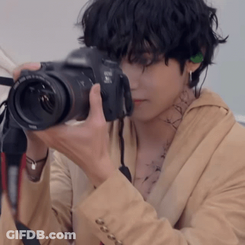 A Man Is Taking A Picture With A Canon Brand Camera GIF