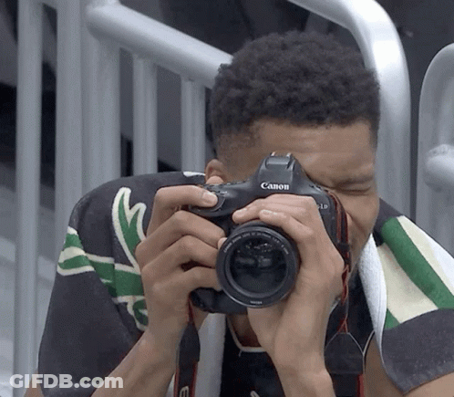 A Man Is Taking A Picture With A Canon Brand Camera GIF