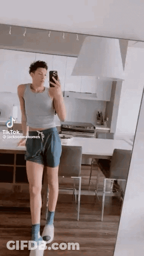 A Man Is Taking A Selfie In A Kitchen In Front Of A Mirror . GIF