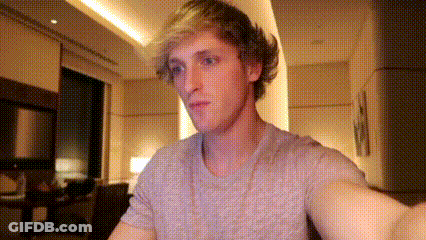 A Man Is Taking A Selfie In A Living Room While Wearing A Gray Shirt . GIF